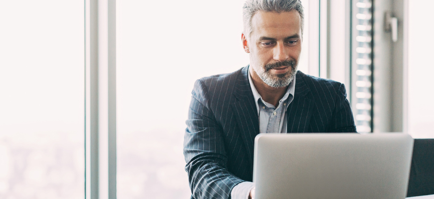 Insurance agent smiling happily as he works on his laptop.