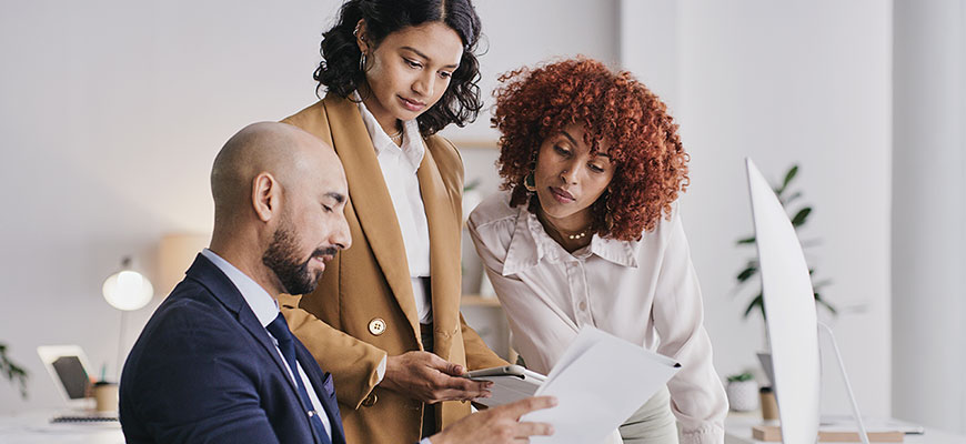 Three professionals reviewing compliance documentation