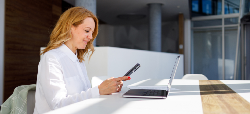 Middle-aged woman working on phone and laptop simultaneously