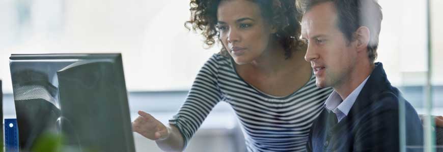Two coworkers looking at a desktop screen with one pointing something out