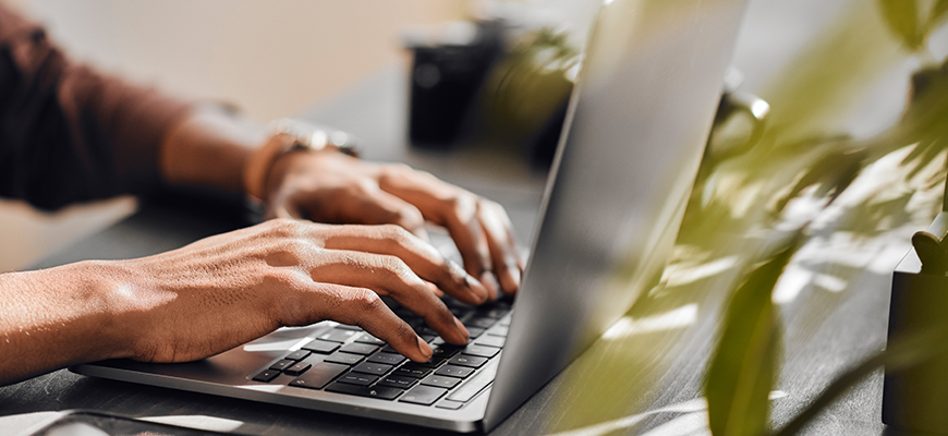 Hands typing on a laptop